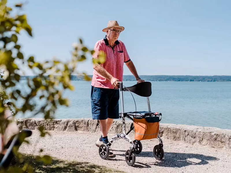 Mann f&auml;hrt mit Rollmobil auf einem Weg neben dem Meer