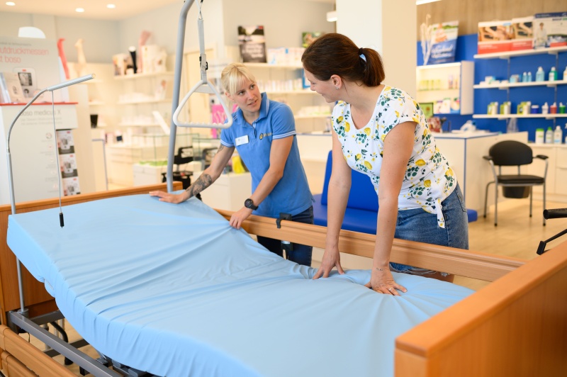 Eine Mitarbeiterin erkl&auml;rt einer Kundin die Handhabung eines Pflegebettes