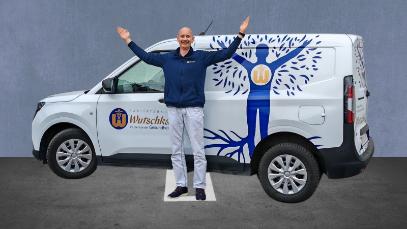 Ein Mitarbeiter steht vor einem Wutschka-Lieferwagen und hebt die H&auml;nde