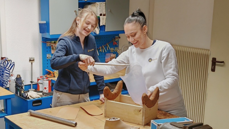 Zwei Mitarbeiterinnen arbeiten l&auml;chelnd in der Werkstatt